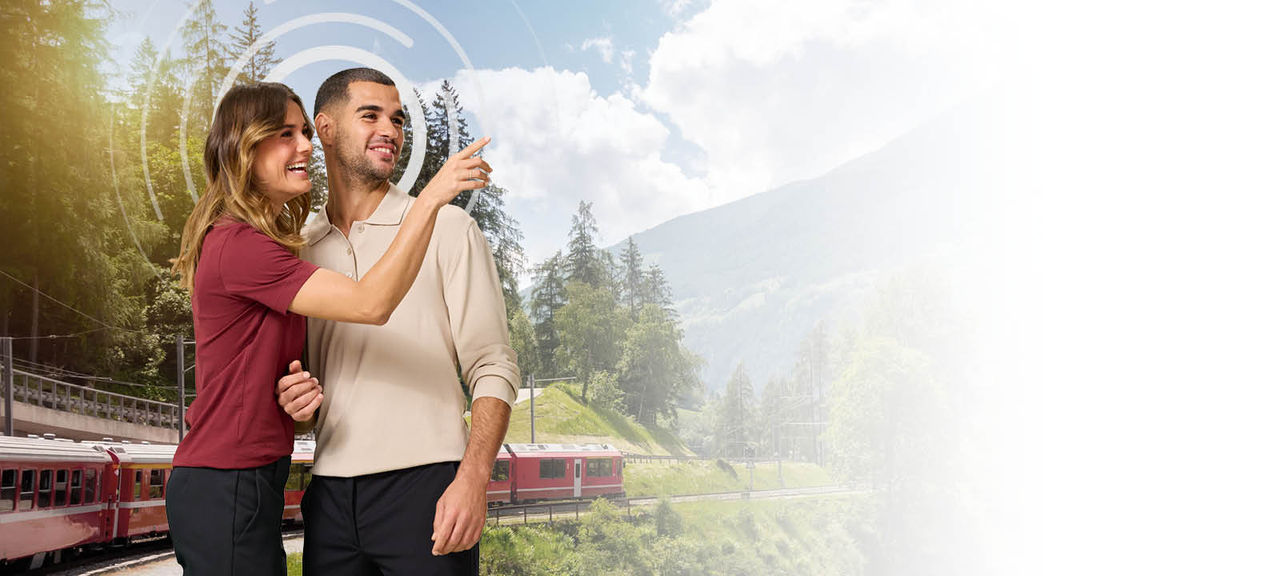 Pareja en un bonito paisaje verde con un tren pasando por detrás