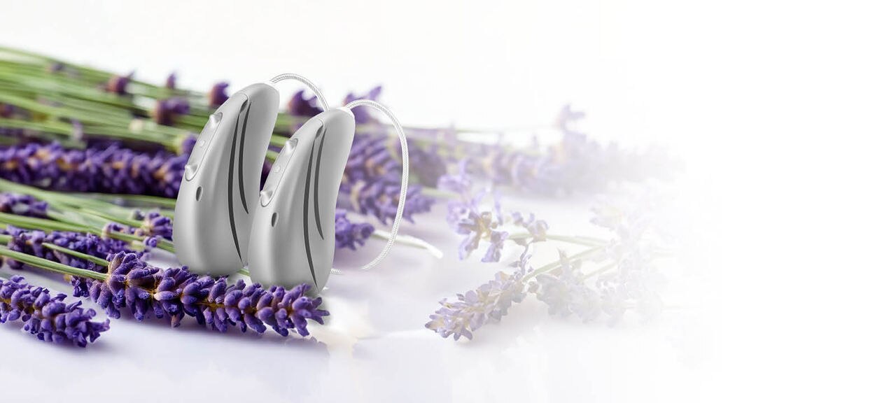 Pair of Hansaton sound E-R hearing aids next to lavender